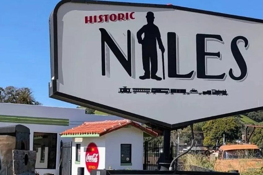 A historic sign with a silhouette of a man, a Coca-Cola sign, and a vintage car. 1