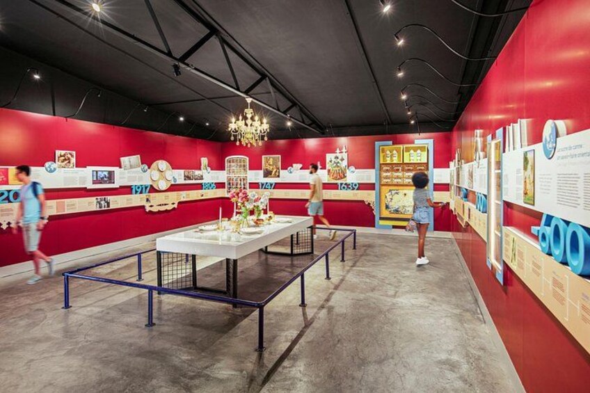 Un espacio de exhibición interior con paredes rojas, paneles informativos y un candelabro. 1