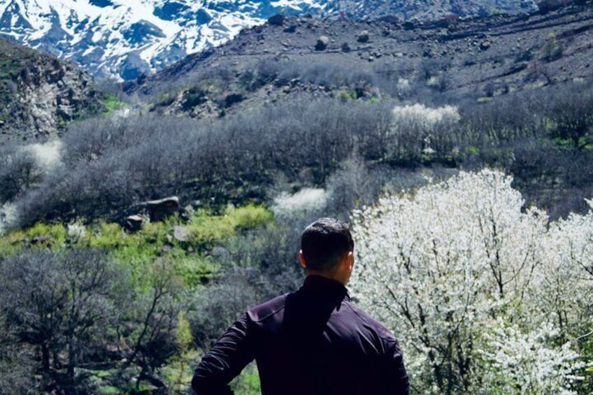 A person standing with a view of a mountainous landscape and a river. 1