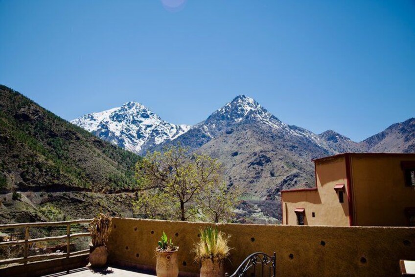 A mountain landscape with snow-capped peaks, a building with a red roof, and potted plants on a balcony. 5