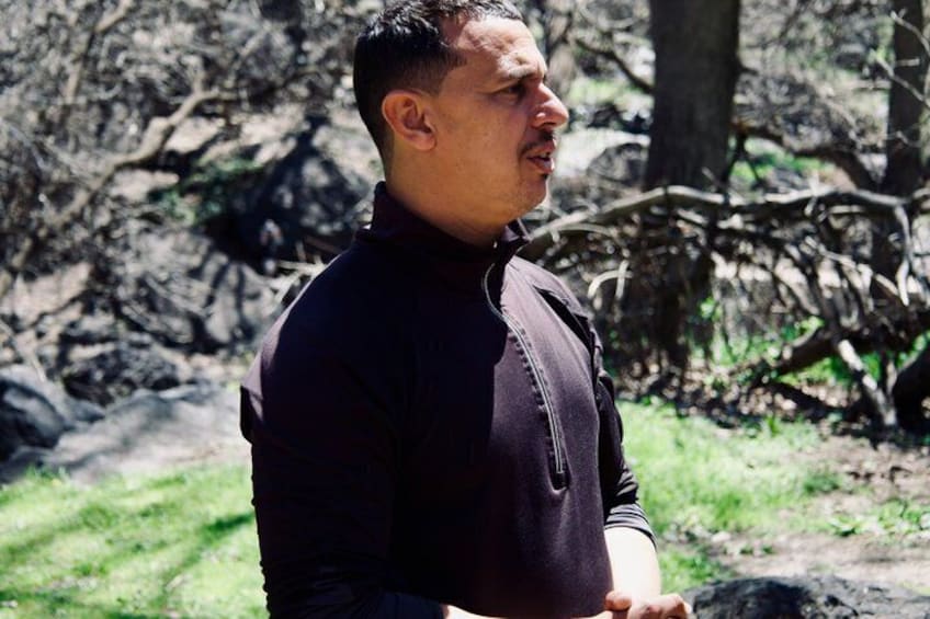 A person standing outdoors with trees and a grassy area in the background. 2