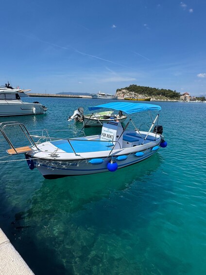 A boat with a blue canopy docked at a pier, surrounded by calm water and other boats. 4