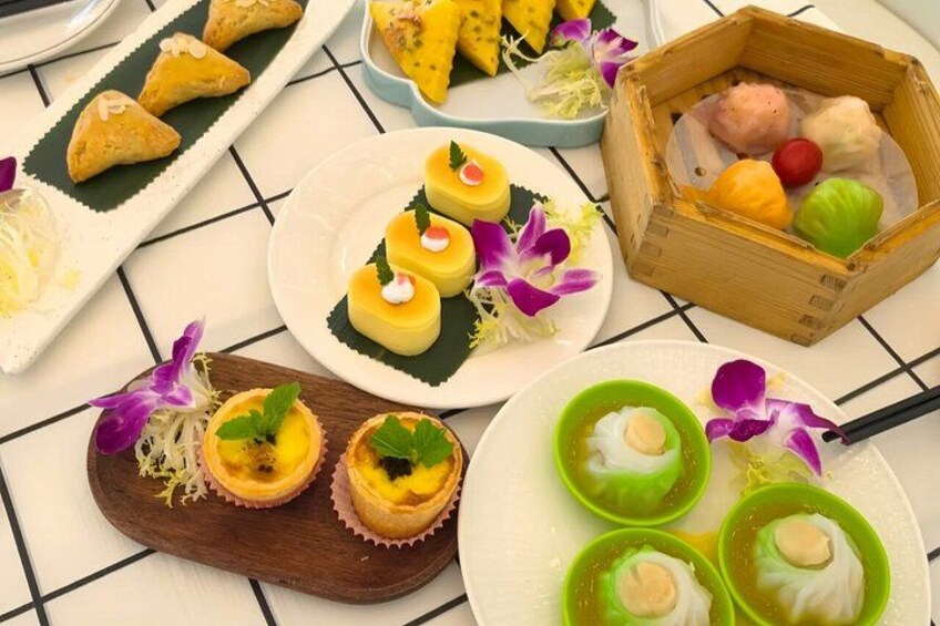 A variety of Asian desserts, including dim sum and small pastries, arranged on a table with a tiled background. 2