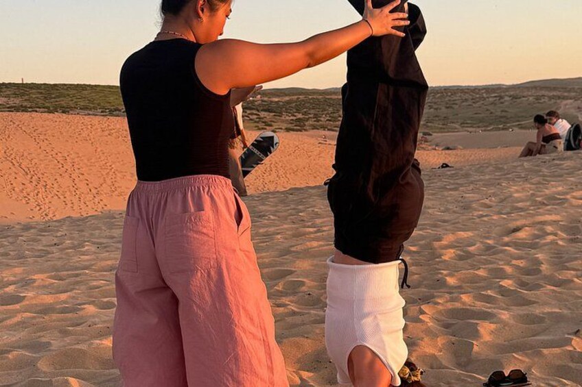 A person adjusting another person's clothing on a sandy beach. 5