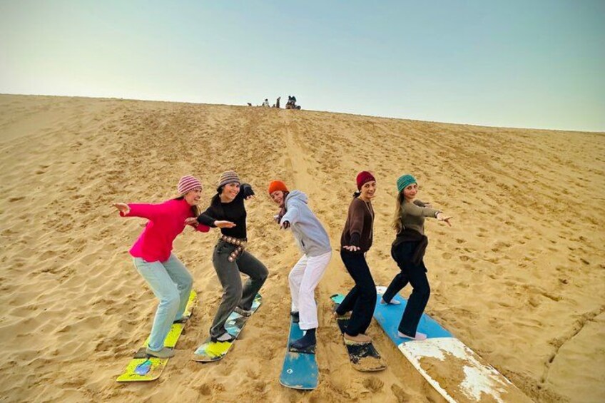 A group of people snowboarding on a sandy slope. 3