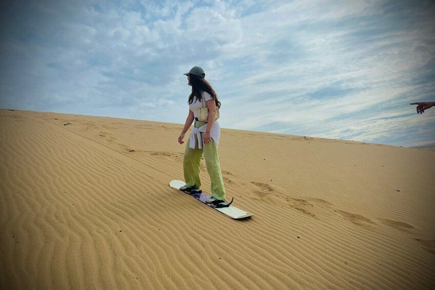 A person snowboarding down a sand dune. 1