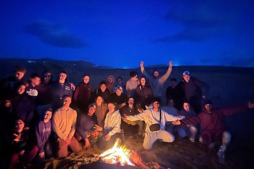 A group of people gathered around a campfire at night. 2