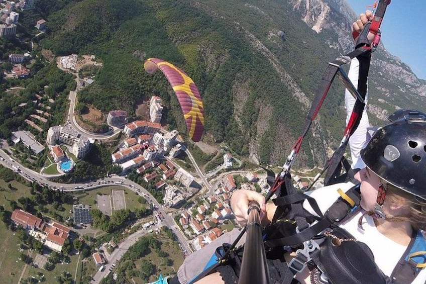 A person paragliding with a colorful parachute, a mountainous landscape, and a town below. 2