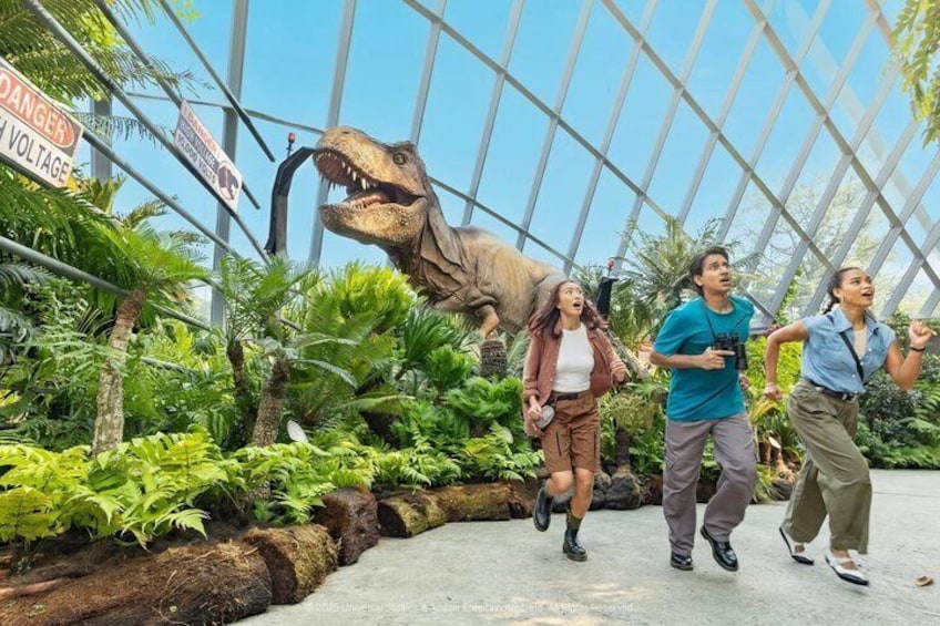 En dinosaur-udstilling med en stor T-Rex model, frodig vegetation og et fareskilt angående højspænding. 2