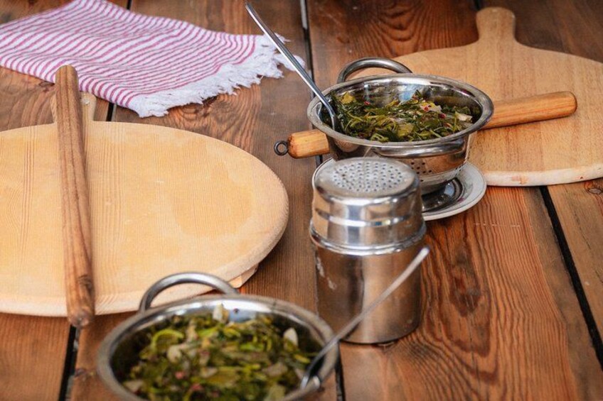 Une table en bois, un rouleau à pâtisserie, une passoire en métal contenant des légumes verts, un salier en métal et une planche à découper en bois. 2