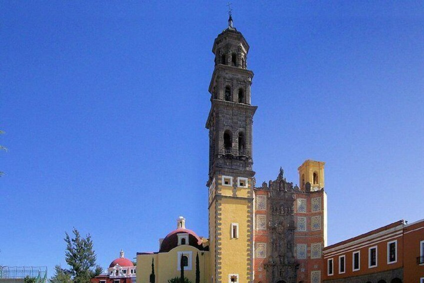 Una torre histórica con un reloj, una iglesia con cúpula roja y un edificio con fachada amarilla. 2
