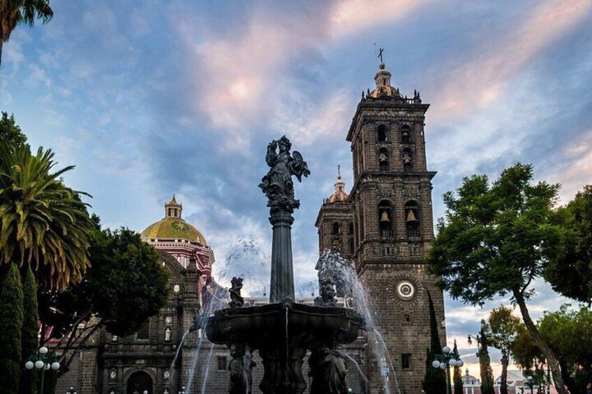 Un edificio histórico con una torre de reloj, una fuente con estatuas y una cúpula. 3