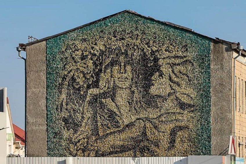En byggnad med en mosaikmålning som föreställer ett träd och en figur. 1