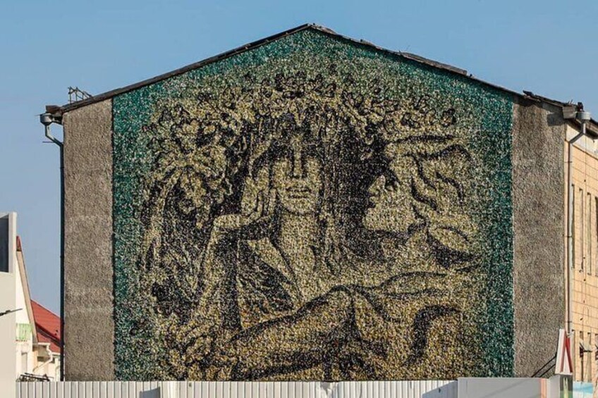 En bygning med et mosaikmaleri af et træ og en figur. 1