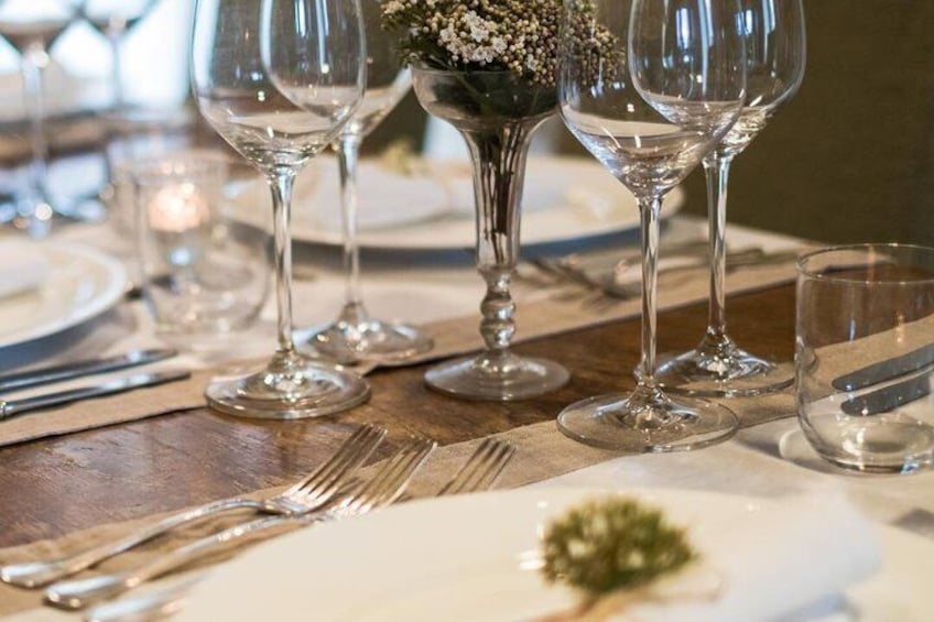 Una mesa dispuesta con copas de vino, tenedores y una pequeña planta decorativa. 2