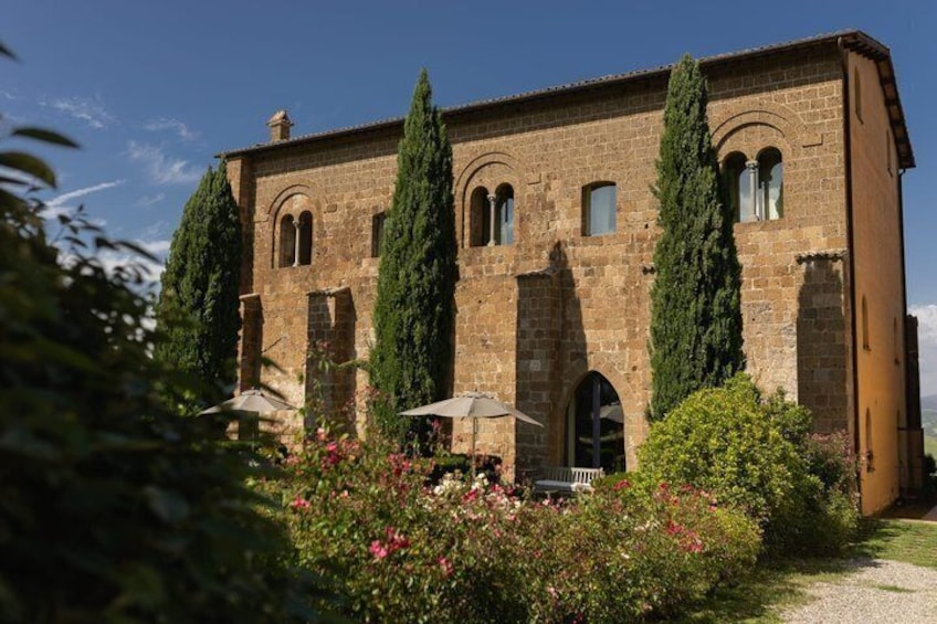 Un edificio histórico de piedra con ventanas de arco y un jardín con flores y árboles. 5