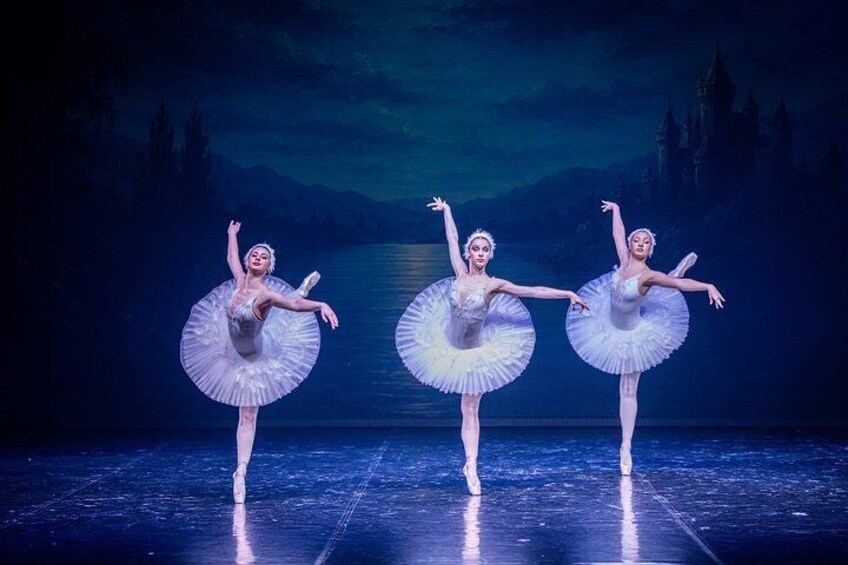 Three ballet dancers in tutus performing on a stage with a dark, castle-like backdrop. 2