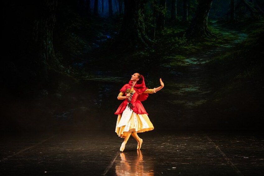 A person performing on a stage with a forest background. 2