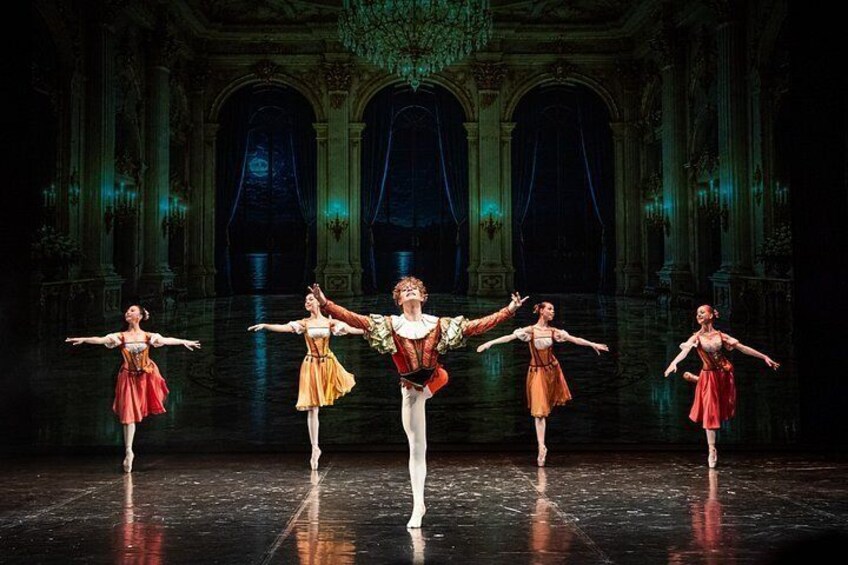 A ballet performance in a grand hall with ornate columns and chandeliers. 5