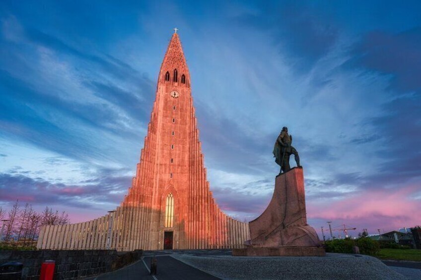 A tall red church with a statue in front. 1