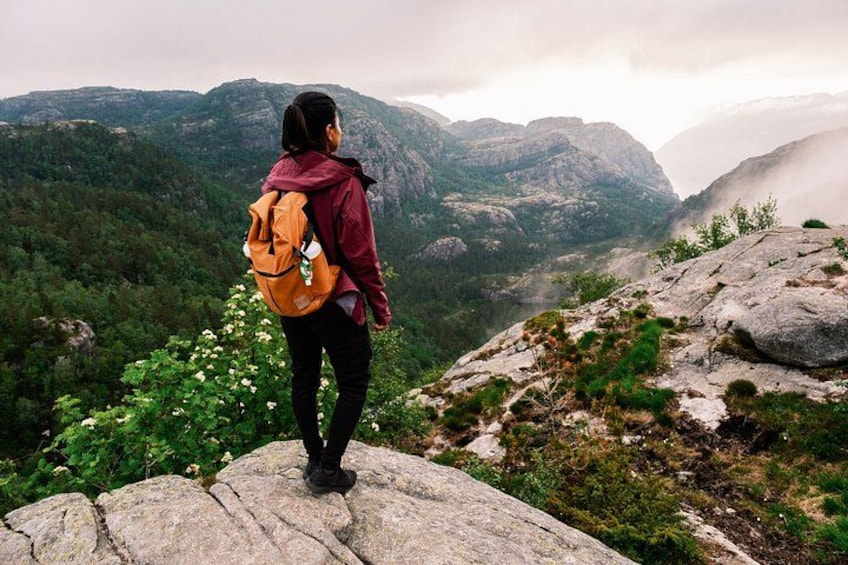 Une personne se tient sur un rocher, un sac à dos sur le dos, et contemple un paysage montagneux. 2
