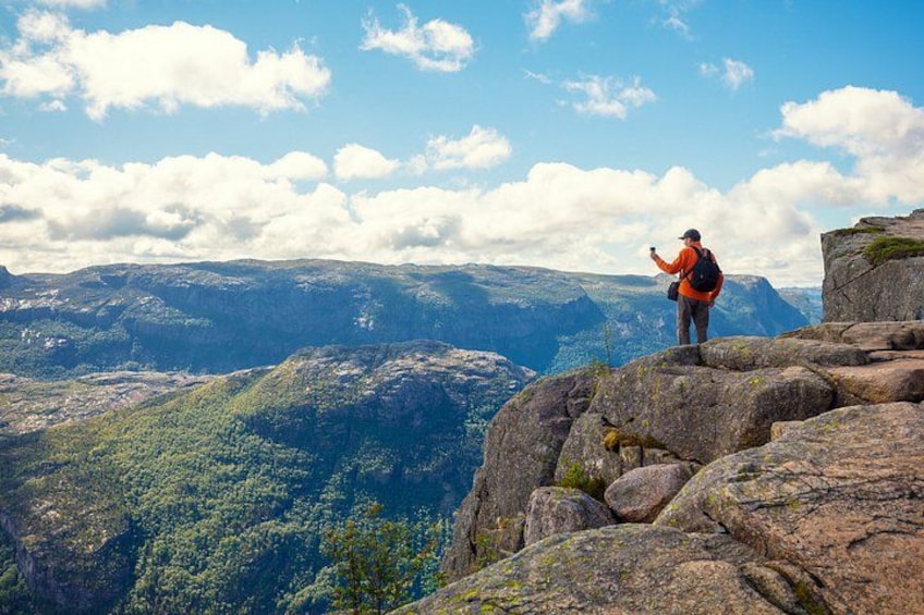 Une personne se tient debout sur un promontoire rocheux, un sac à dos sur le dos, et contemple un paysage montagneux. 5