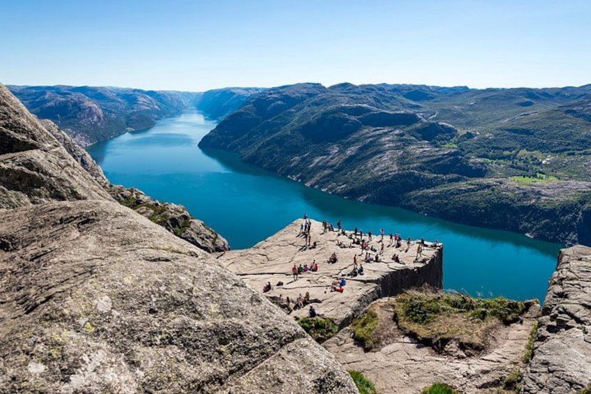 Une falaise rocheuse surplombe un lac paisible, lui-même entouré de collines. 1