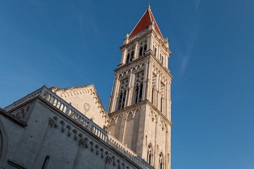 A historic building with a prominent tower featuring intricate architectural details and a red roof. 4