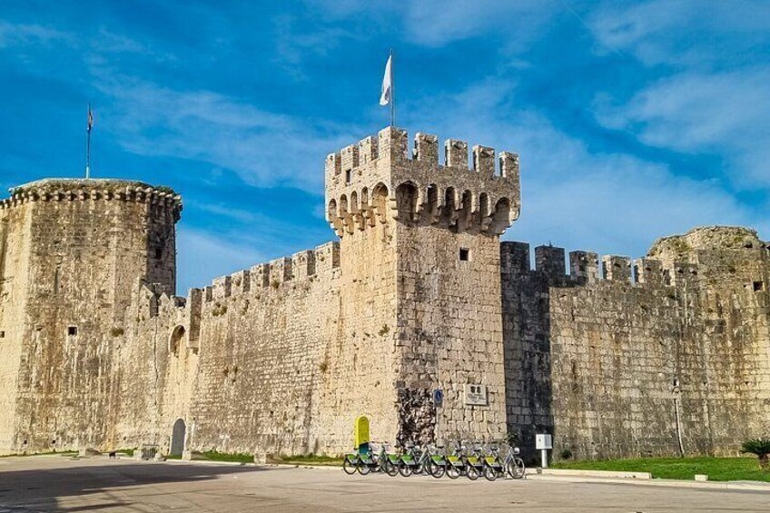 A historic stone castle with a round tower and a flag atop the central tower. 3