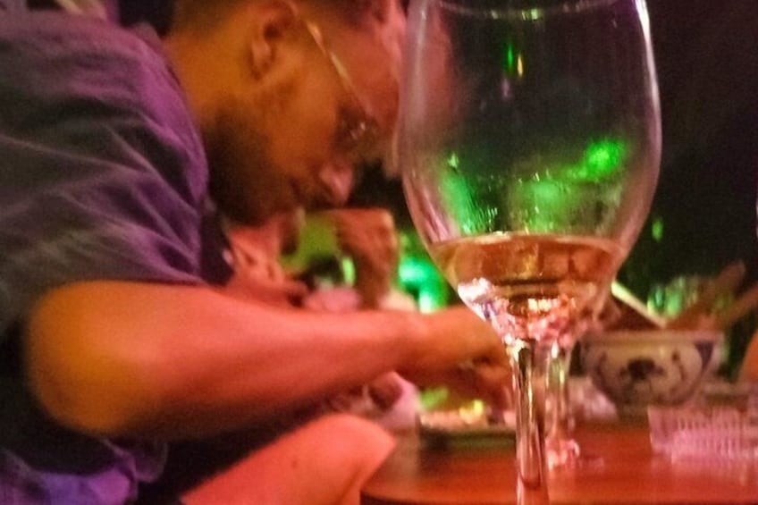 A person sitting at a table with a glass of white wine. 2