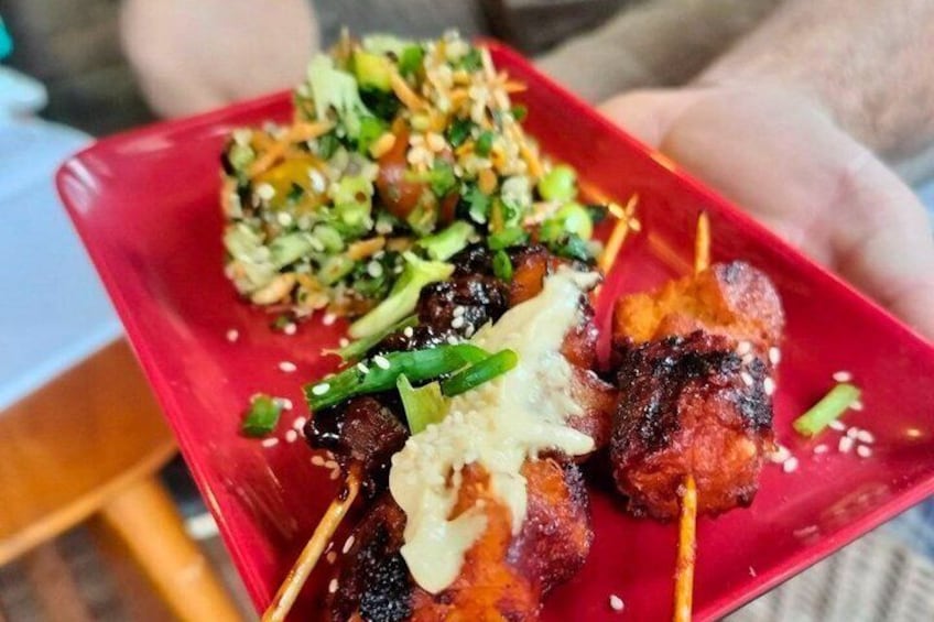 A red plate with skewered meat, a side of rice, and a green salad. 5