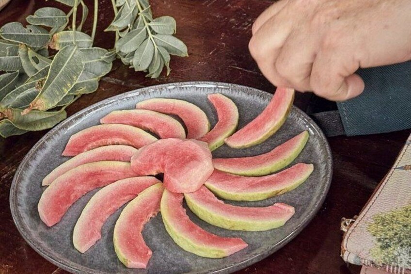 A hand arranging watermelon slices on a plate. 4