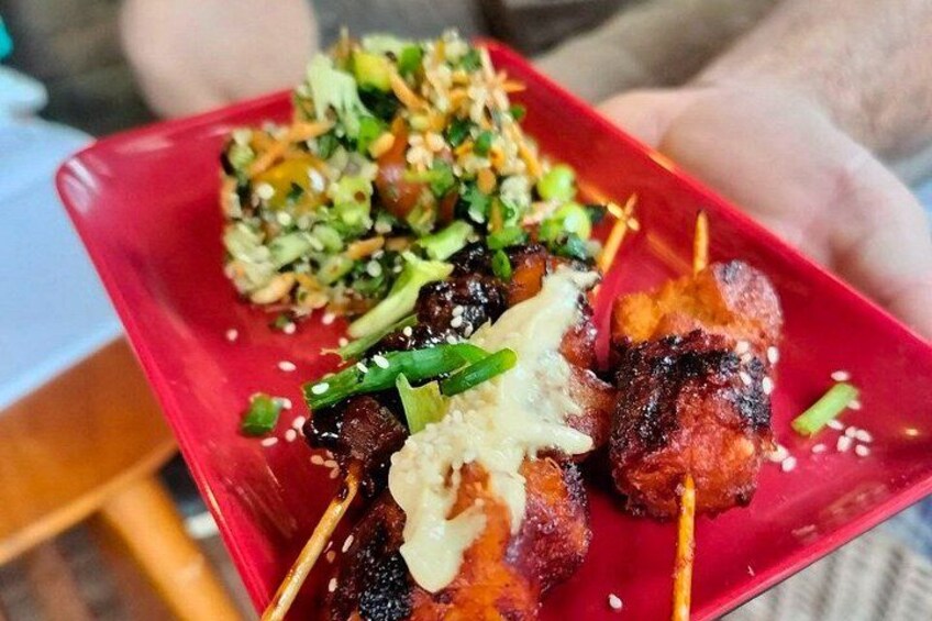 A red plate with skewered meat, a side of rice, and a green salad. 3