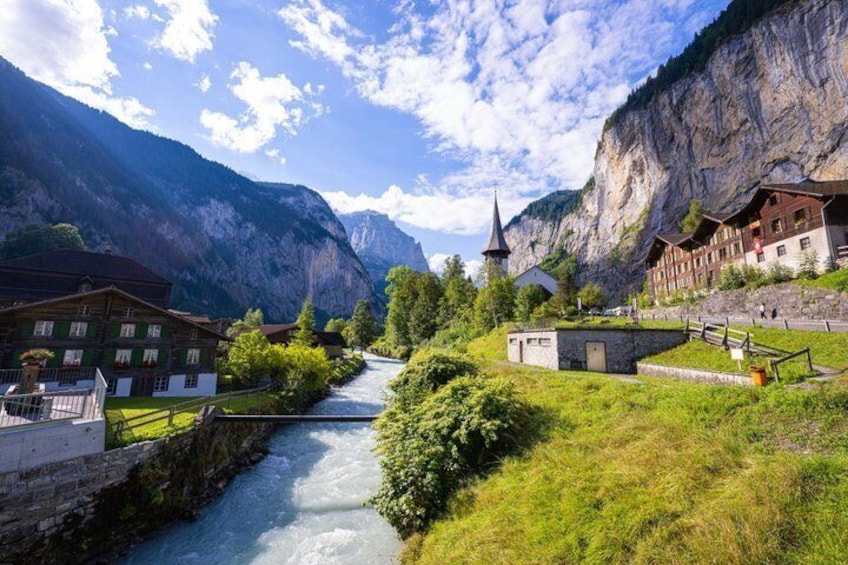 A river flowing through a valley with buildings on the banks, surrounded by mountains. 5