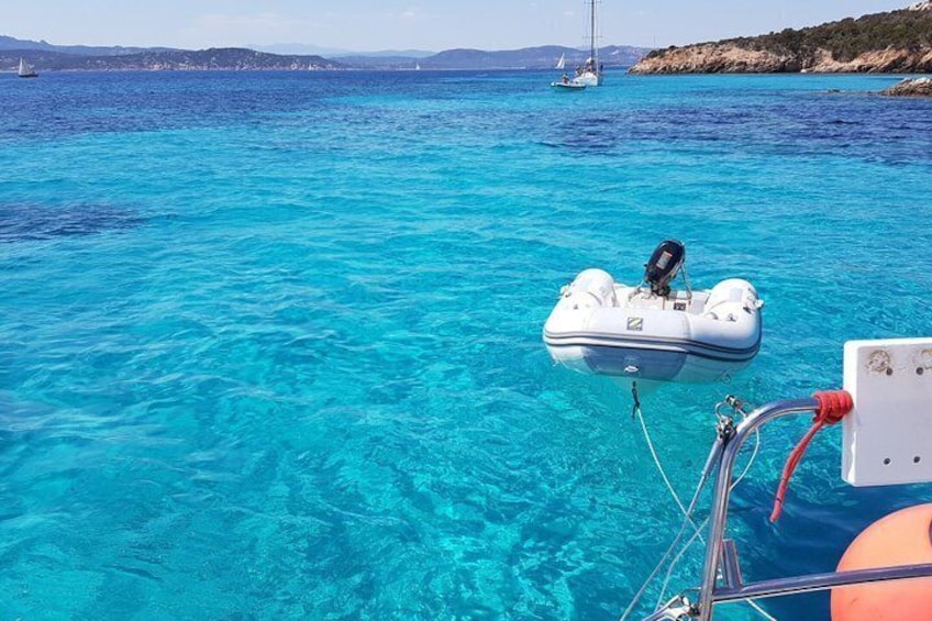A clear blue sea with a boat and a sailboat in the distance. 3
