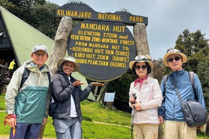 Ein Schild im Kilimanjaro-Nationalpark, das die Höhe der Mandara Hütte und Wanderzeiten zu verschiedenen Punkten angibt. 5
