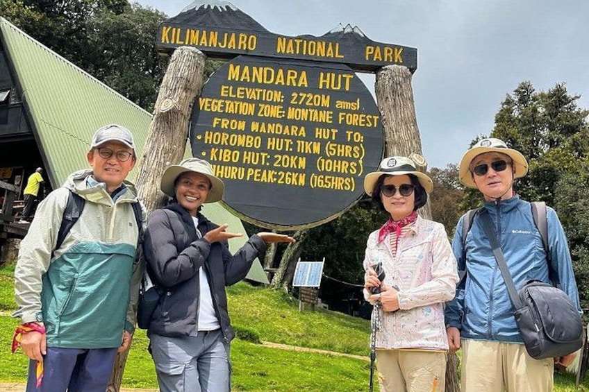 A sign at Kilimanjaro National Park with information about Mandara Hut, including elevation and hiking times to other huts. 2