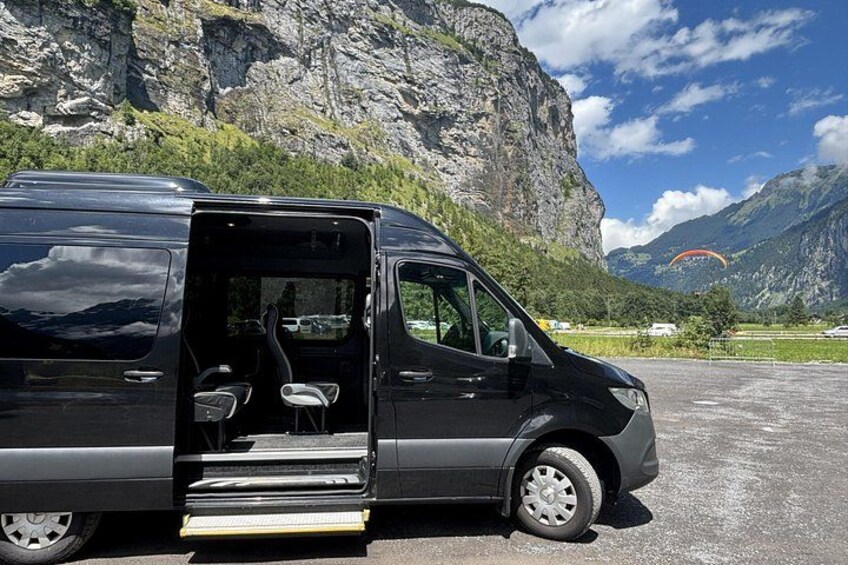 A black van parked in a mountainous area with a rocky cliff in the background. 5