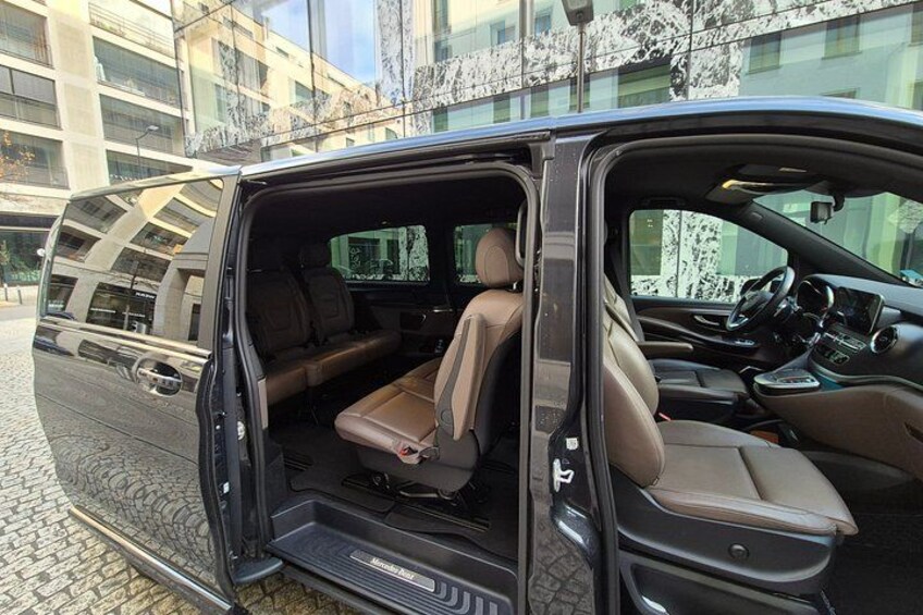A van with its door open, revealing a spacious interior with leather seats and a central console. 2