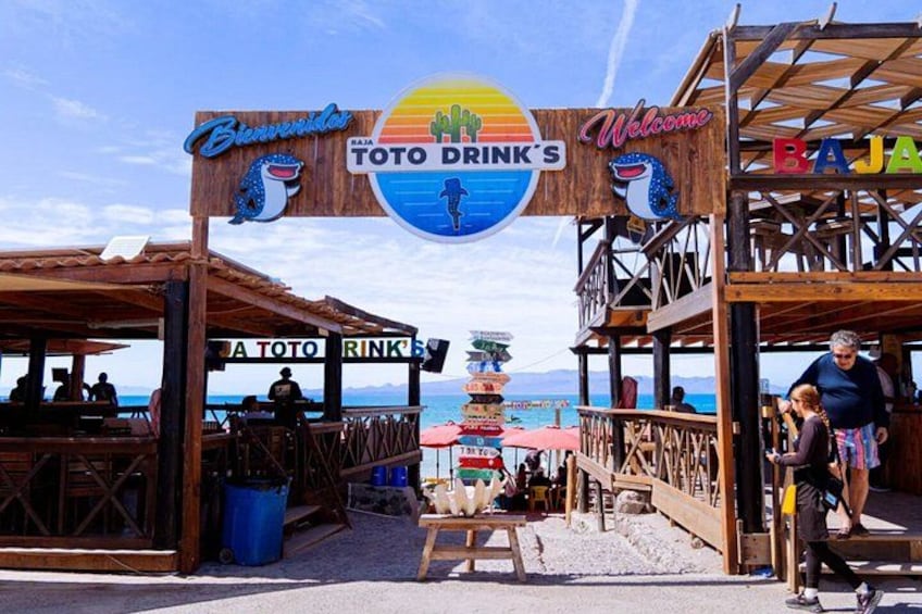 Un bar frente al mar llamado Toto Drink's, con estructura de madera, asientos al aire libre y vista al océano. 3