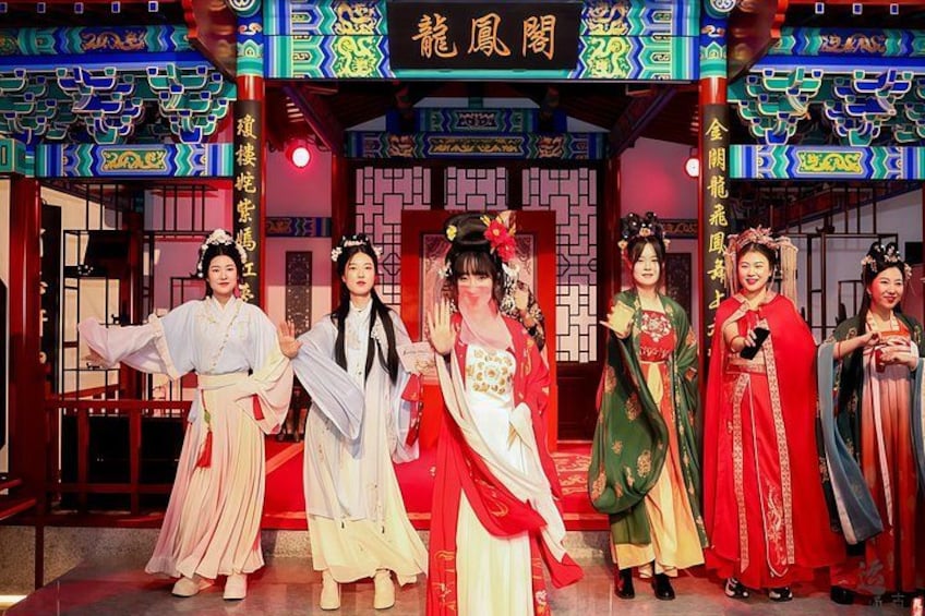 A group of people in traditional Chinese attire performing on a stage with a backdrop of Chinese architecture. 1