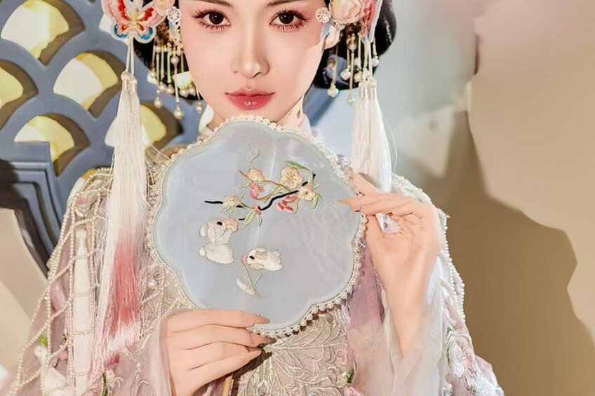 A person holding a decorative fan with floral embroidery. 3