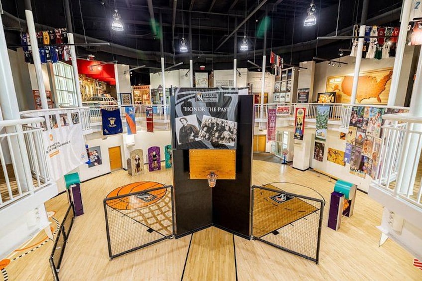 A sports-themed indoor exhibition with basketball hoops, a large poster, and various sports memorabilia. 4