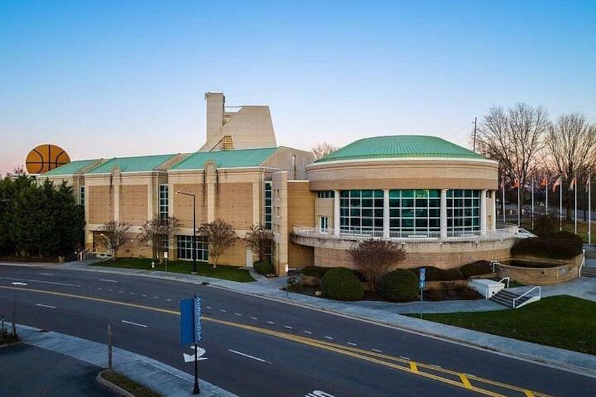 A building with a green roof and large windows, surrounded by a road and greenery. 5