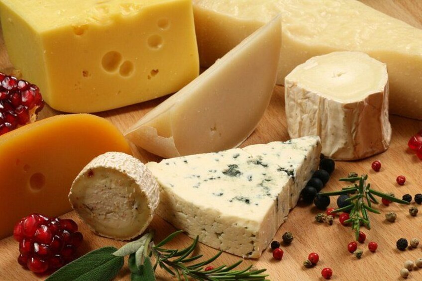 Verschiedene Käsesorten, darunter ein Blauschimmelkäse, auf einer Holzplatte mit Kräutern und Beeren. 4