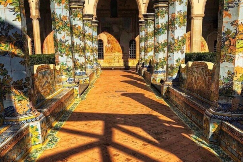 An ornate corridor with tiled columns and arches, leading to a central point. 1