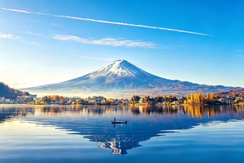 A calm lake with a reflection of a mountain, a person rowing a boat, and a town in the foreground. 2