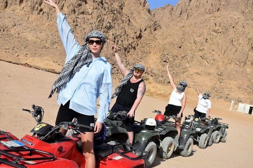 A group of people with ATVs in a desert landscape. 2