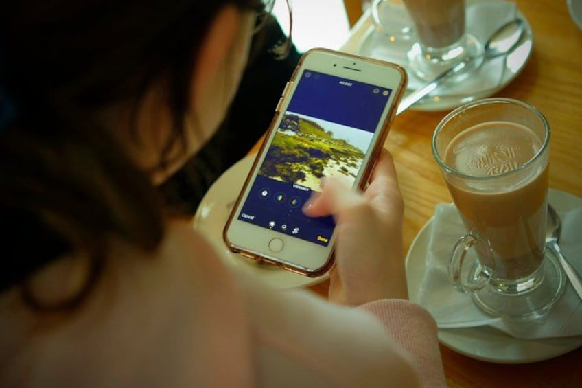 A person using a smartphone at a table with a glass of coffee. 3