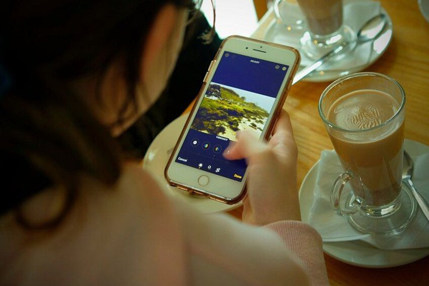 A person using a smartphone at a table with a glass of coffee. 2